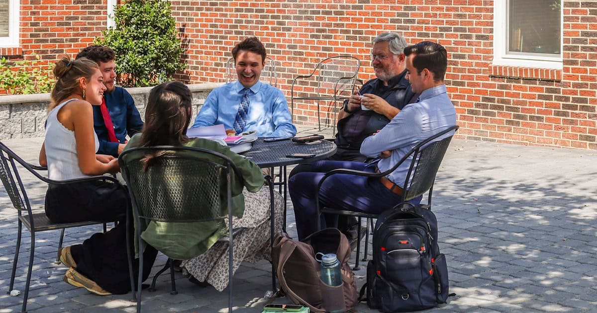 College Chaplain Fr. Marcus Pollard engages in conversation with students on the new patio outside St. Lawrence Commons.